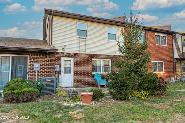 back of property with a yard and central AC unit