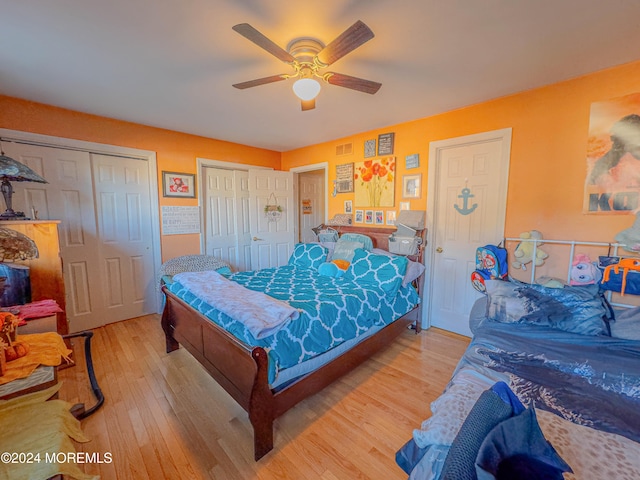 bedroom featuring ceiling fan, two closets, and light hardwood / wood-style flooring