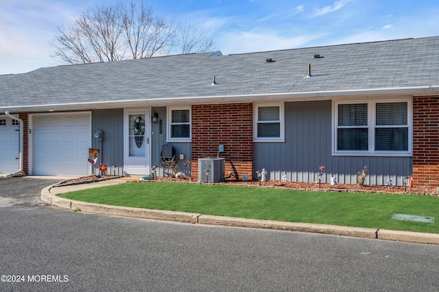 ranch-style house featuring a front yard, central AC, and a garage