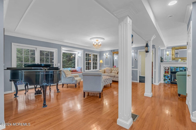 living room featuring a chandelier, light hardwood / wood-style flooring, ornate columns, and ornamental molding