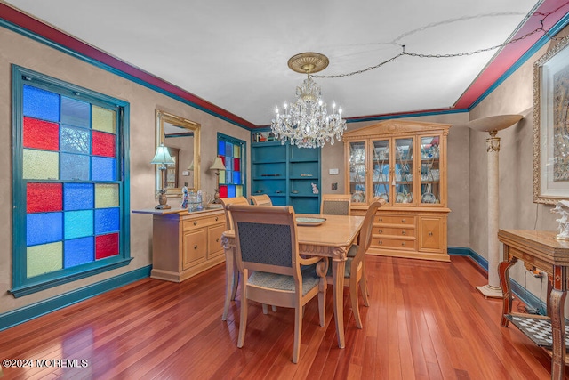 dining area featuring light hardwood / wood-style flooring, a chandelier, built in features, and ornamental molding