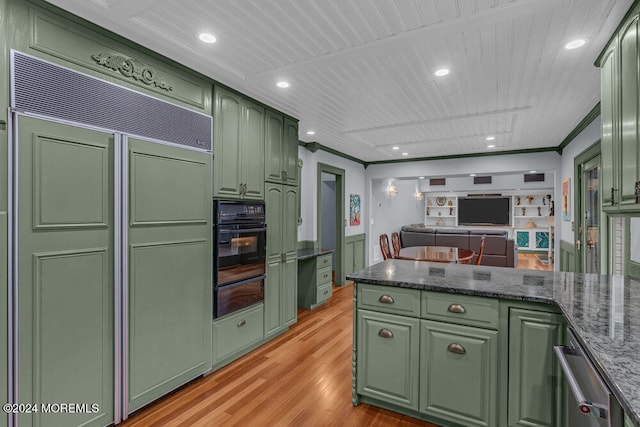 kitchen with oven, paneled built in fridge, light wood-type flooring, and green cabinetry