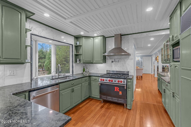 kitchen featuring wall chimney exhaust hood, green cabinets, and appliances with stainless steel finishes