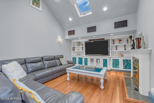 living room with a fireplace, wood-type flooring, a skylight, and high vaulted ceiling