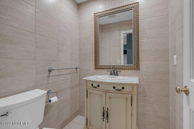 bathroom with vanity, tile walls, and toilet