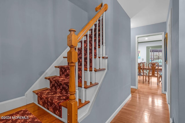 staircase with hardwood / wood-style floors and vaulted ceiling