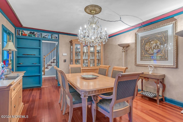 dining room featuring an inviting chandelier, ornamental molding, sink, and light hardwood / wood-style flooring