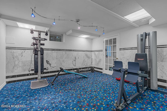 workout area featuring crown molding and tile walls