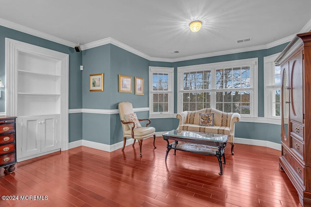 sitting room featuring hardwood / wood-style floors, built in features, and ornamental molding