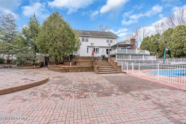 rear view of property featuring a fenced in pool