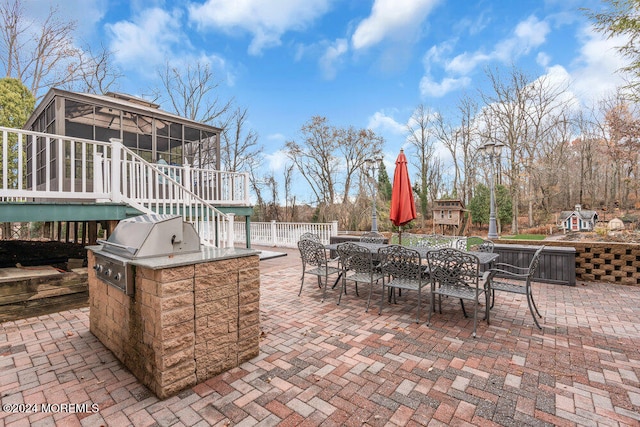 view of patio featuring area for grilling, a sunroom, a wooden deck, and a grill