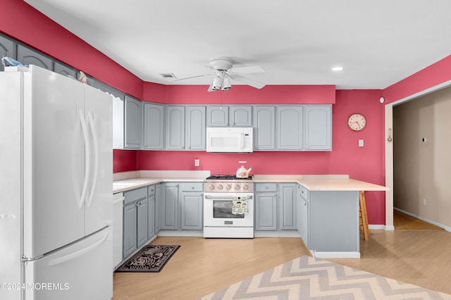 kitchen with ceiling fan, gray cabinets, light wood-type flooring, and white appliances