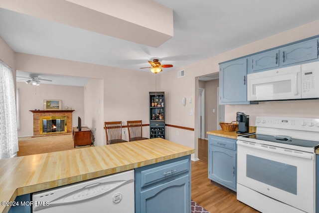 kitchen with white appliances, ceiling fan, light wood-type flooring, a fireplace, and blue cabinetry