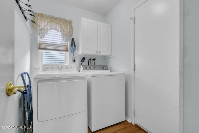 laundry room featuring washing machine and dryer, cabinets, and light hardwood / wood-style floors