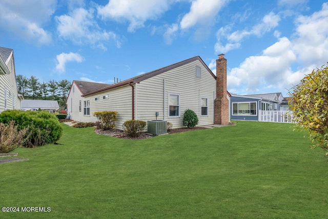 rear view of property featuring a yard and central AC unit