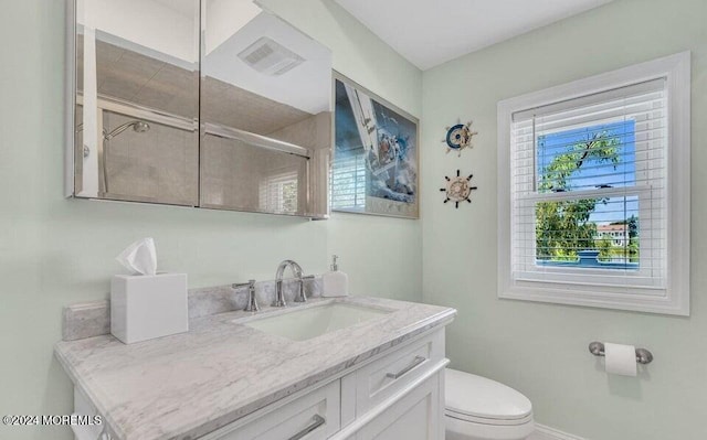 bathroom with toilet, an enclosed shower, and vanity