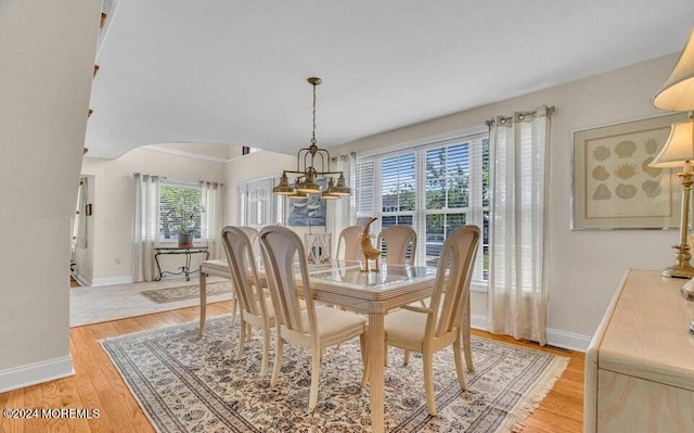 dining space with plenty of natural light, light hardwood / wood-style floors, and an inviting chandelier