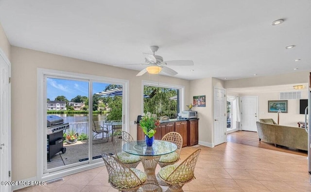 tiled dining space featuring ceiling fan and a water view