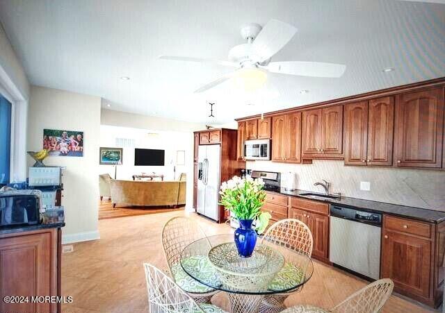 404 Ocean Rd, Spring Lake, NJ 07762 - kitchen featuring appliances with stainless steel finishes, a sink, dark countertops, ceiling fan, and brown cabinetry