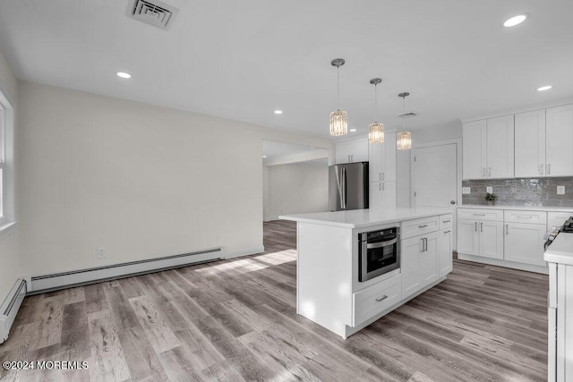 kitchen with light wood-type flooring, appliances with stainless steel finishes, a baseboard radiator, a kitchen island, and white cabinetry