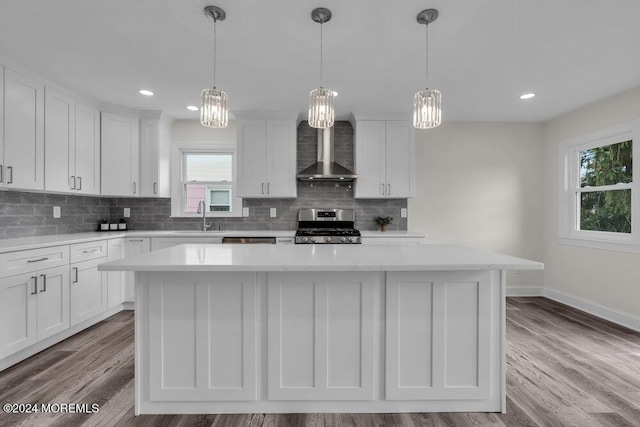 kitchen with white cabinetry, wall chimney range hood, a wealth of natural light, and gas range