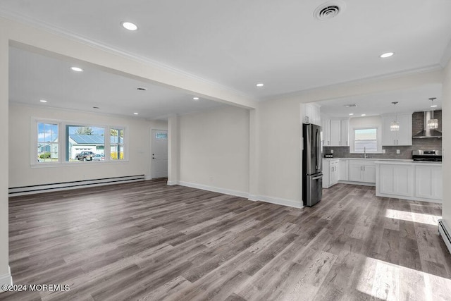 unfurnished living room with light hardwood / wood-style floors, crown molding, sink, and a baseboard heating unit