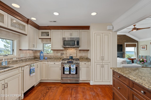 kitchen with light hardwood / wood-style floors, light stone countertops, stainless steel appliances, and vaulted ceiling