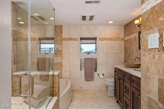 full bathroom featuring toilet, vanity, separate shower and tub, and tile walls