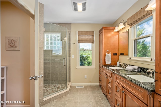 bathroom with tile patterned floors, plenty of natural light, walk in shower, and vanity