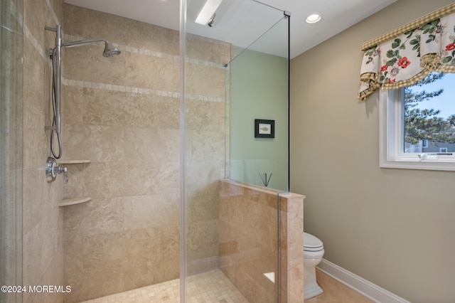 bathroom featuring a tile shower, tile patterned flooring, and toilet