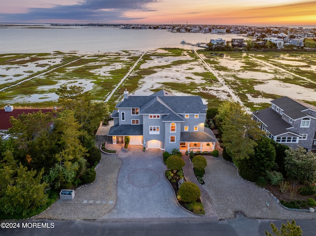 aerial view at dusk featuring a water view