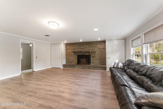 living room with a wood stove, crown molding, and light hardwood / wood-style flooring