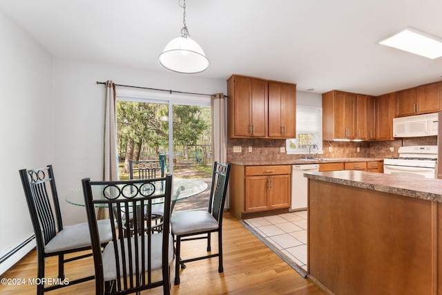 kitchen featuring hanging light fixtures, white appliances, light hardwood / wood-style flooring, and a wealth of natural light