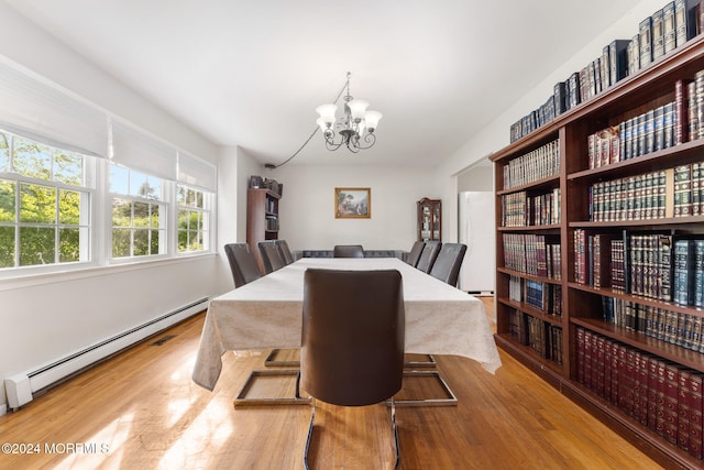 dining area featuring hardwood / wood-style floors, baseboard heating, and an inviting chandelier