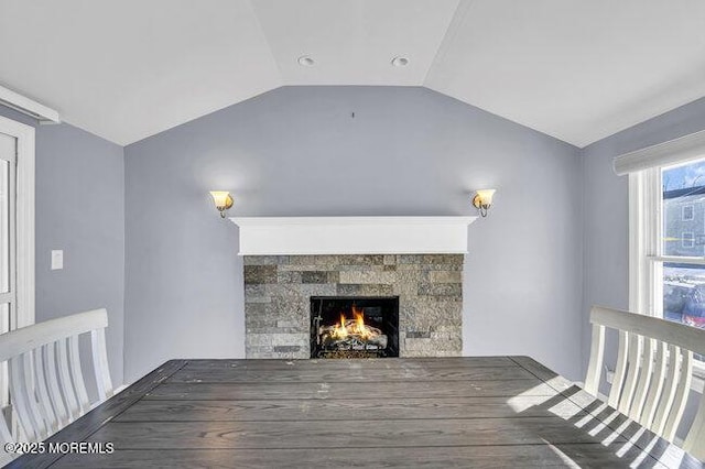 interior space featuring a tiled fireplace and vaulted ceiling