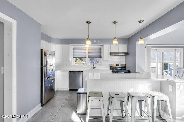 kitchen with white cabinetry, appliances with stainless steel finishes, decorative backsplash, a breakfast bar, and sink