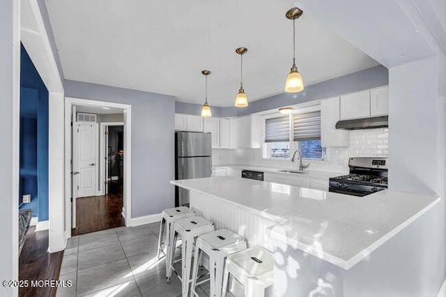 kitchen featuring pendant lighting, white cabinets, stainless steel appliances, sink, and a breakfast bar