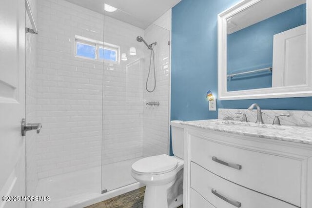 bathroom with toilet, vanity, and a tile shower