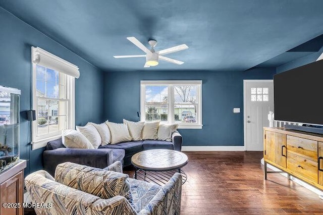 living room featuring ceiling fan, dark wood-type flooring, and a healthy amount of sunlight