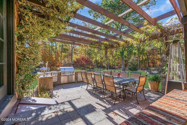 view of patio with exterior kitchen, area for grilling, and a pergola