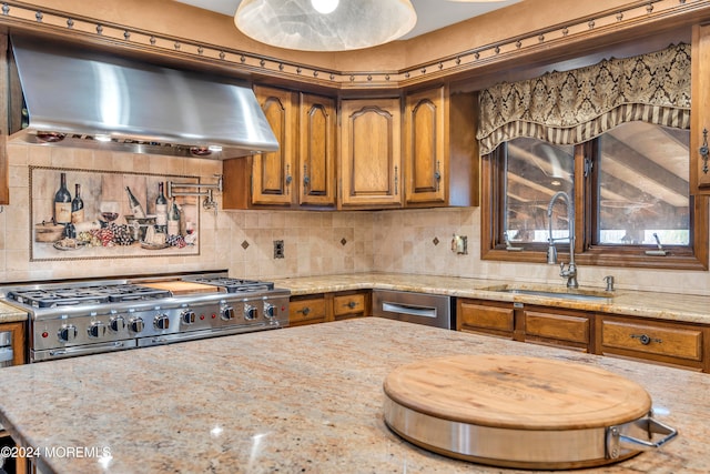 kitchen featuring light stone countertops, stainless steel range, sink, wall chimney range hood, and decorative backsplash