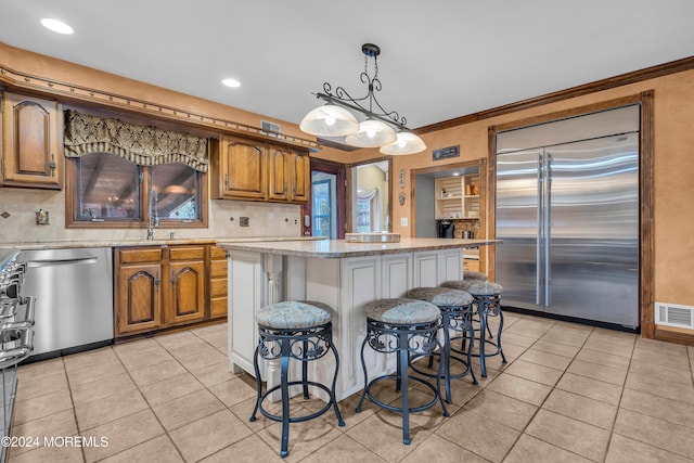 kitchen with a center island, a kitchen bar, ornamental molding, and stainless steel appliances