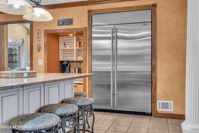 kitchen with white cabinetry, built in fridge, light tile patterned floors, and decorative light fixtures