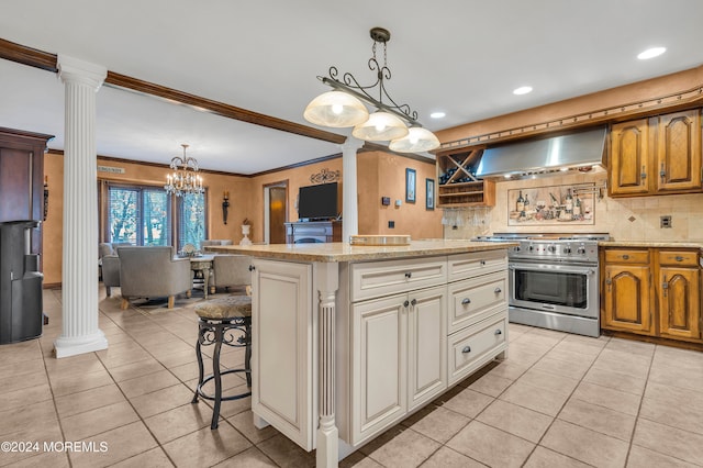 kitchen with a center island, stainless steel stove, decorative columns, and range hood