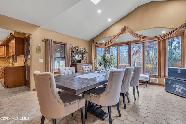 tiled dining space featuring a wealth of natural light, sink, and lofted ceiling