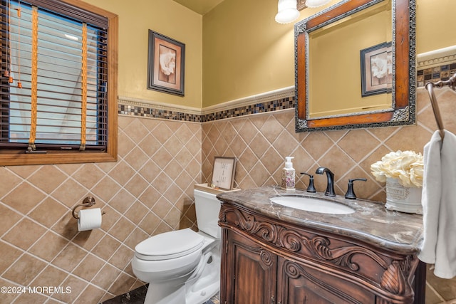 bathroom featuring vanity, tile walls, and toilet