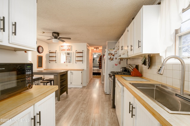 kitchen with gas range, ceiling fan, sink, light hardwood / wood-style flooring, and white cabinets