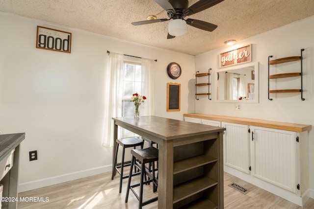 kitchen featuring wooden counters, white cabinets, light hardwood / wood-style flooring, ceiling fan, and a textured ceiling