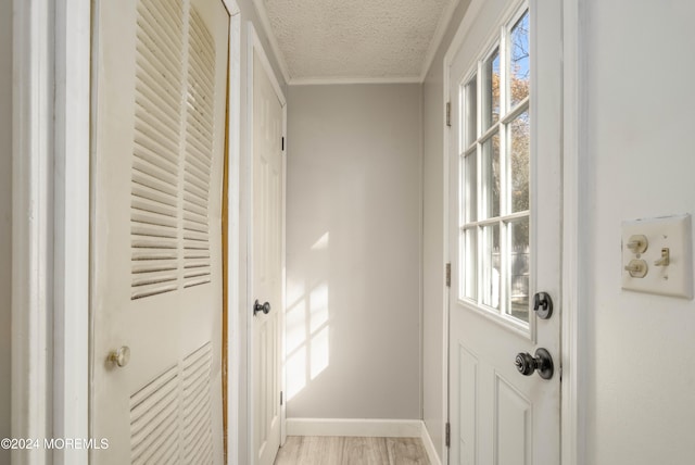 doorway with crown molding, light hardwood / wood-style flooring, and a textured ceiling