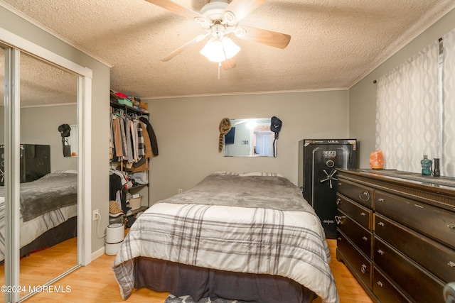 bedroom with ceiling fan, ornamental molding, light wood-type flooring, a textured ceiling, and a closet